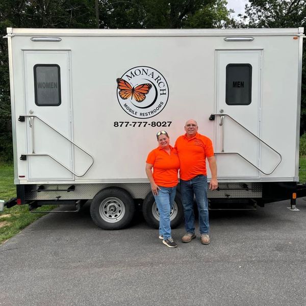employees standing outside mobile restroom unit