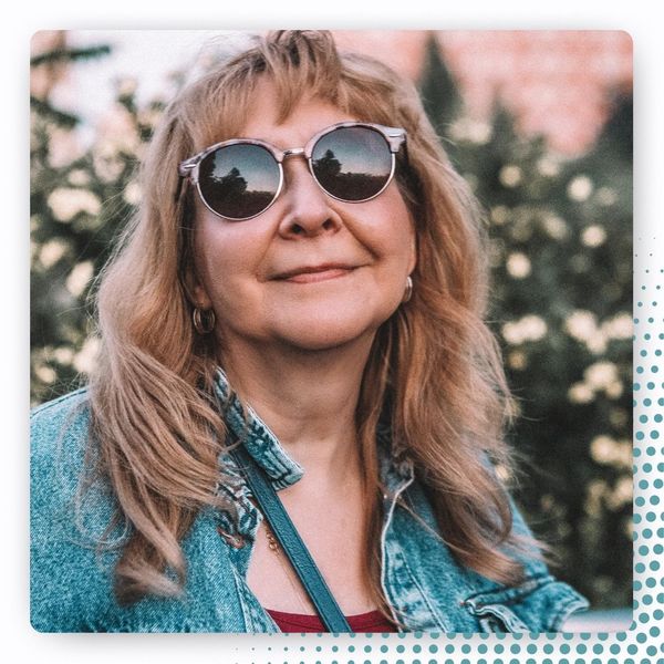 smiling woman with dark round sunglasses and denim jacket