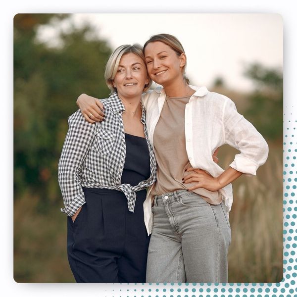 middle-aged woman with younger woman, smiling outdoors, looking into distance