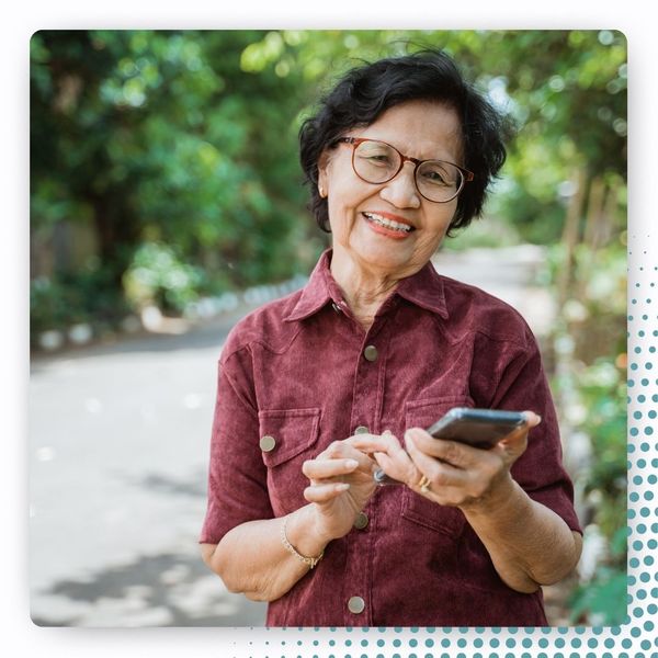 older woman happy outdoors, using phone