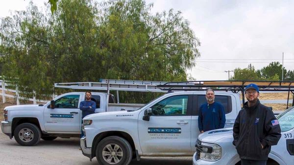 The family leadership team at Black Knight Termite & Pest Control standing in front of company service trucks in Riverside County.
