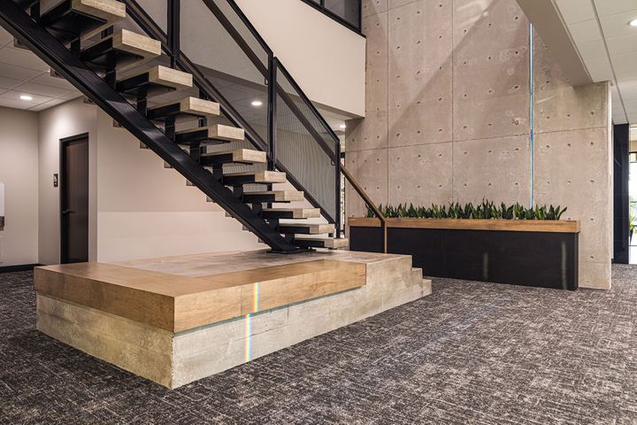 Architectural staircase design at Hoeft Builders in Eau Claire, WI featuring custom poured-in-place concrete staircase and interior precast wall. Office architectural staircase at Hoeft Builders in Eau Claire, WI