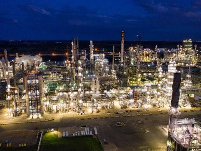 Aerial night view of a sprawling, brightly lit oil refinery and industrial processing facility. Aerial night view of a sprawling, brightly lit oil refinery and industrial processing facility.