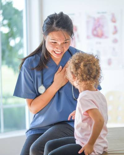 A nurse smiling while talking to a young patient